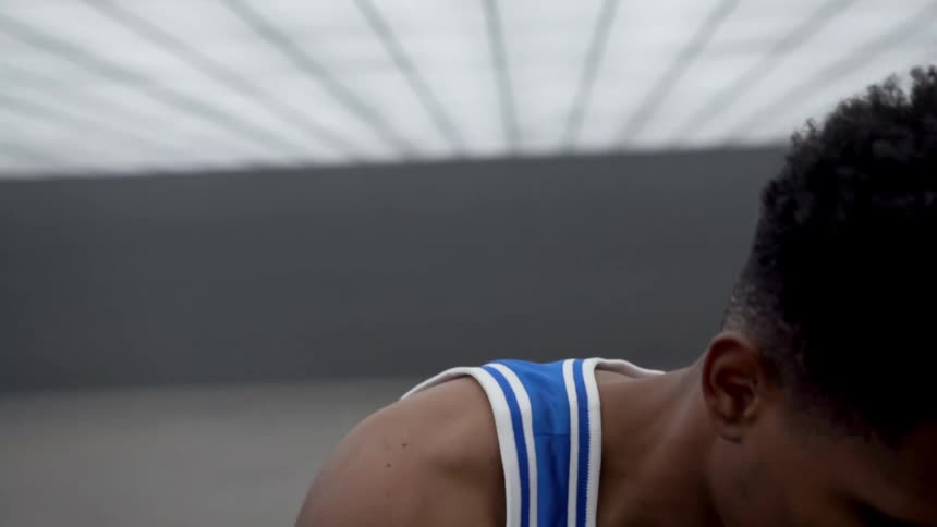 A basketball player dribbles In a futuristic room