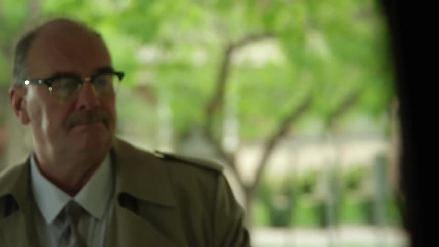 Elderly man with a trim mustache and glasses walks up to a door to ring the bell