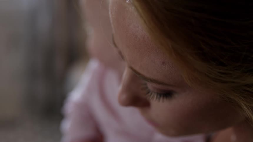 Mother looking upset as she is holding her baby girl and using a smart phone to make a phone call