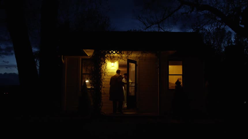 A man walks up to a house and knocks and is let in