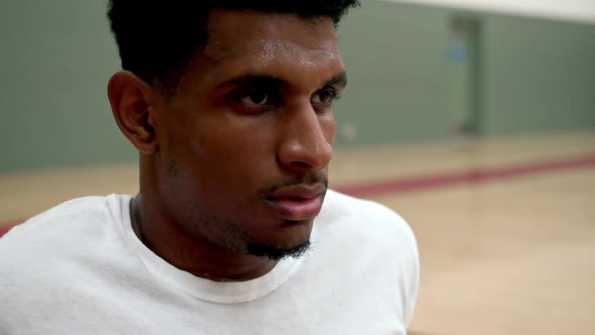 A man is sweating and resting on the basketball court