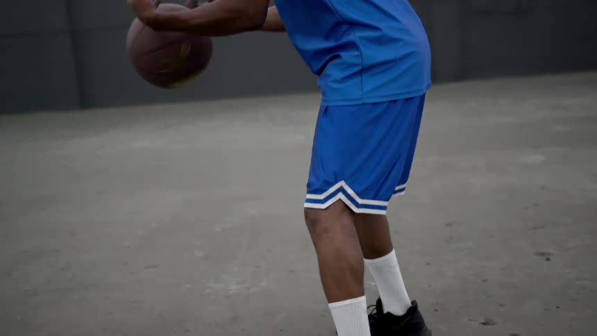A teenager dribbles and spins a basketball indoors