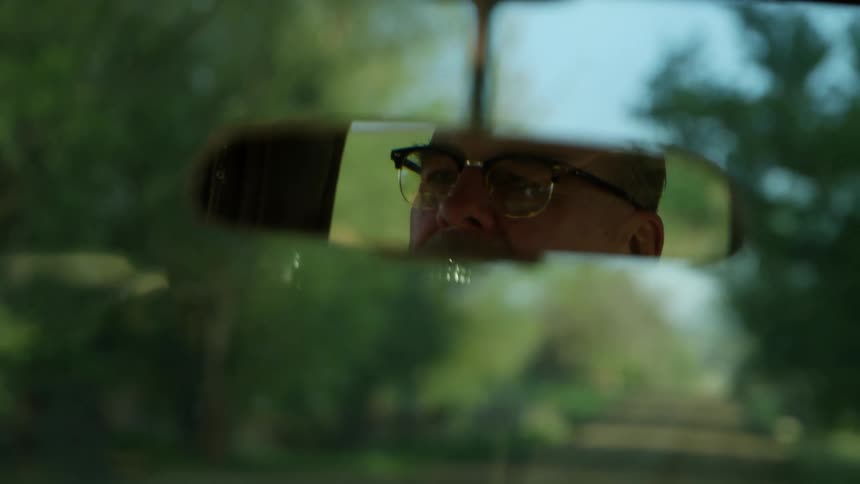 A mans reflection in a rear view mirror as he drives