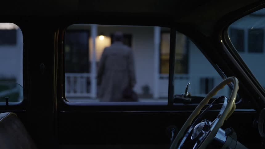 A man walks away from his car and towards a house