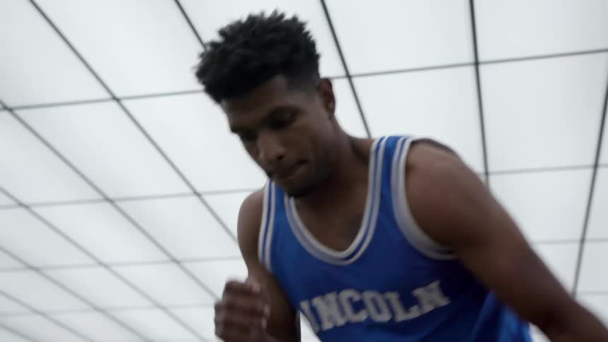 A teenager shows off his dribbling skills in a room with a well lit ceiling