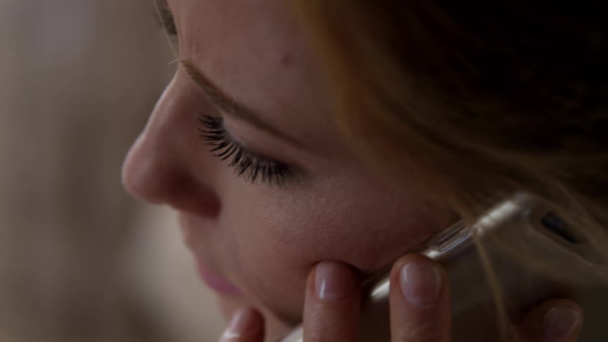 Stressful woman with brown hair talks on a smartphone