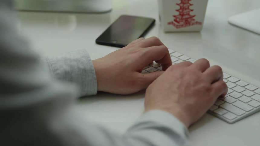 Man sitting at desk types on a keyboard in the office