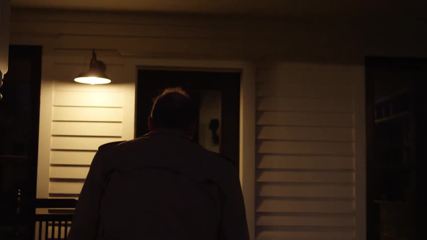 A man is walking into a house at night