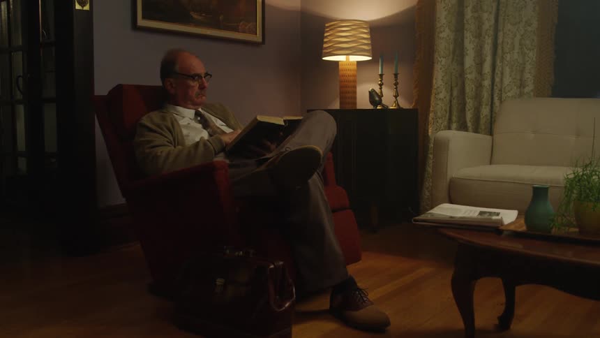 A man sits and reads a book while wearing a suit and tie