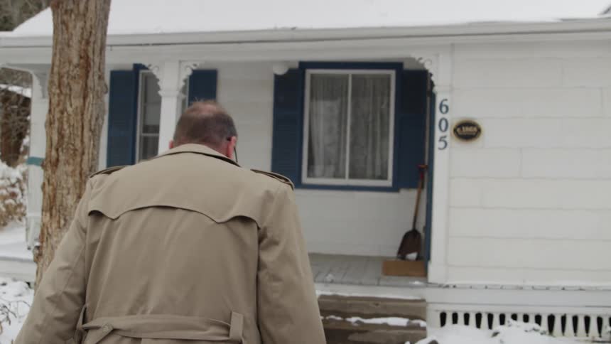 A man walks the sidewalk up to a home