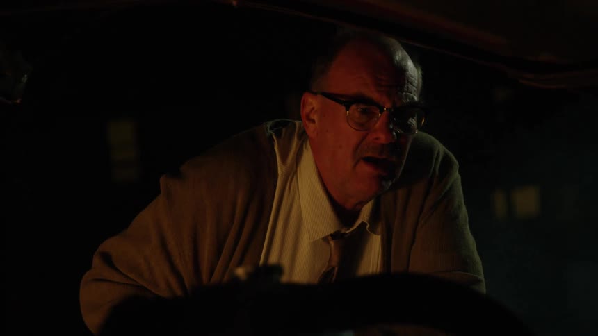 Elderly man checks car engine at the side of the road at night
