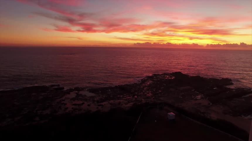 View of a lighthouse at the edge of a beach and a sunset