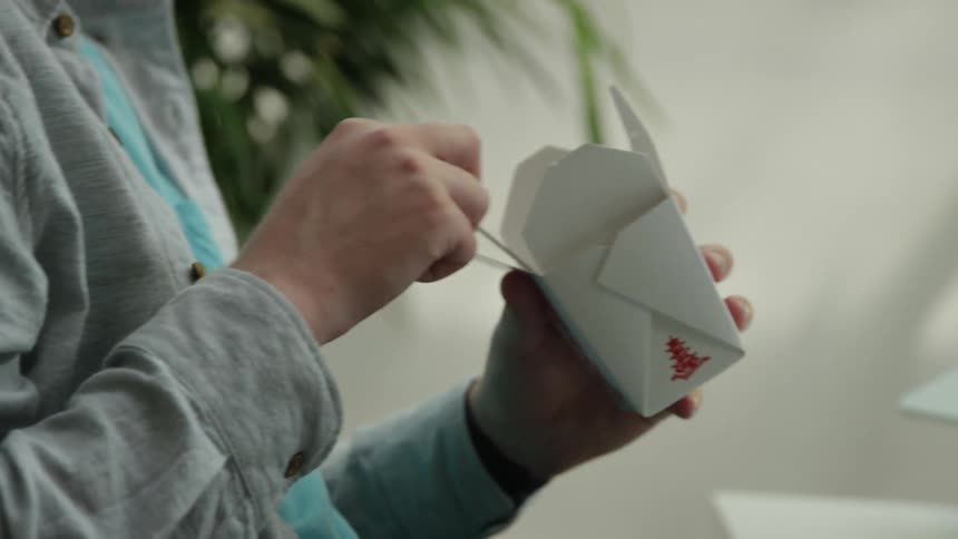 Person sits at table eating food from chinese takeout box