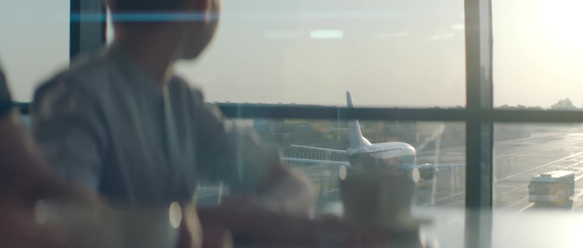Kid watching airplanes taxi on tarmac during sunrise