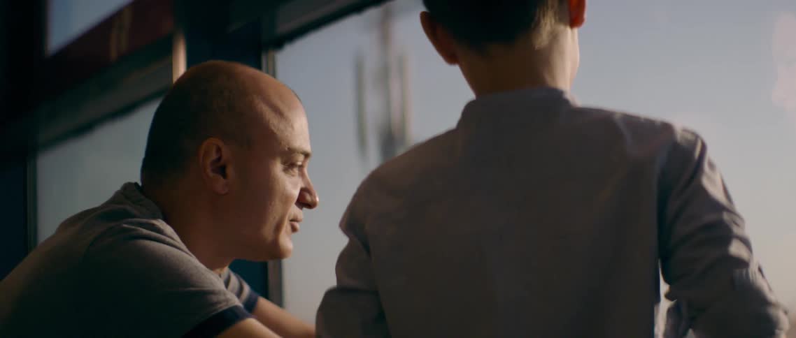 Father and son talking near the window on an airport at sunrise