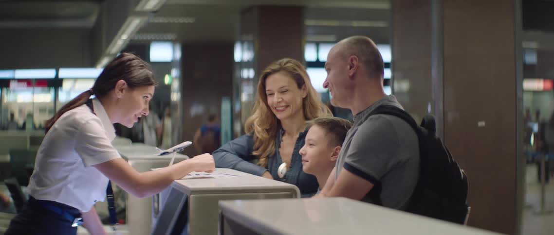 Family buy plane tickets on an airport desk
