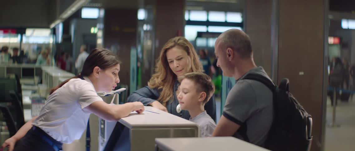 Family on the check in desk of an airport talking to an employee