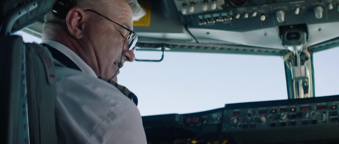 A pilot sits in the cockpit of an airplane and talks