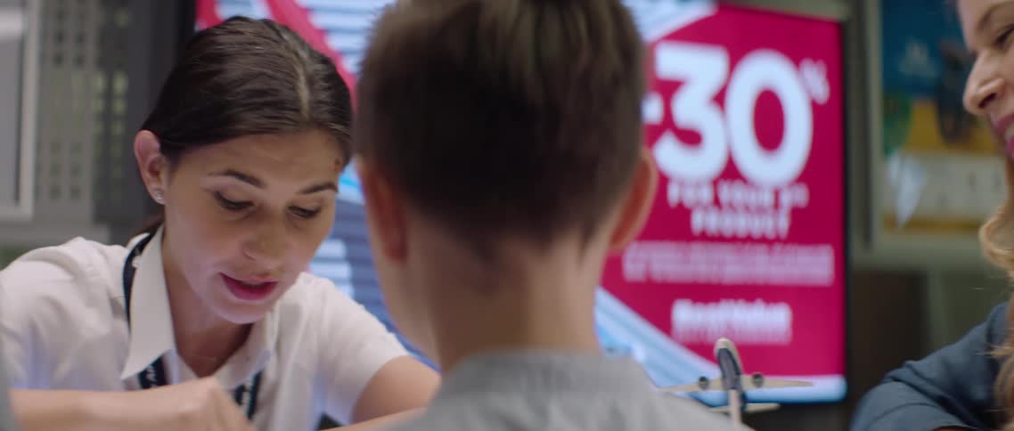 A woman at an airline talks to a young boy