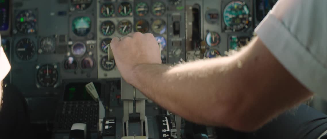 A pilot moves a lever in an airplane cockpit