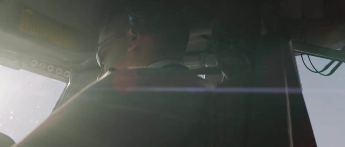 Person occupies vehicle cabin near windows showing blue sky and letting sun glare in