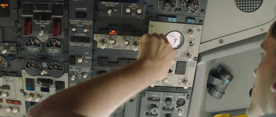 A pilot pulls switches in the cockpit