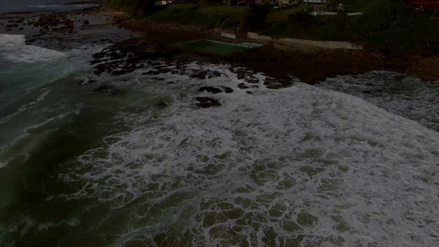Aerial view of an ocean leading up to some houses by the shore