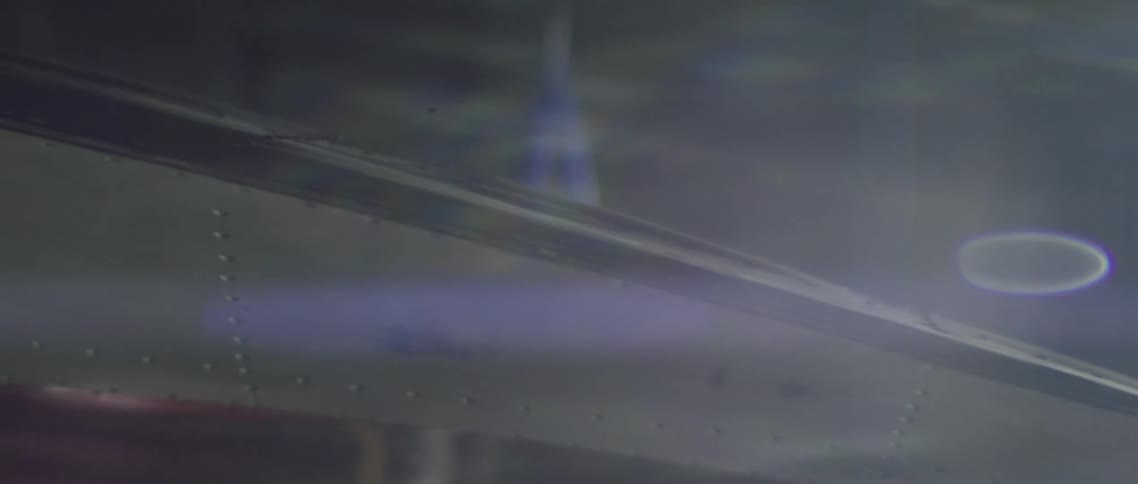 A curved piece of metal with rivets reflects the light shining around it