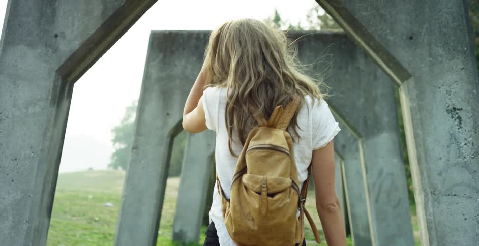 A woman walks under the stone arches on the field