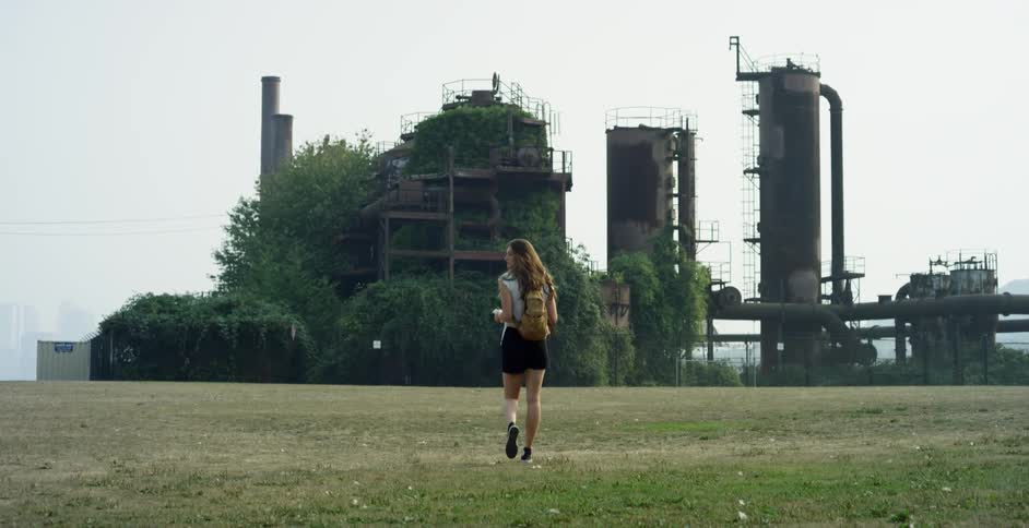A teenager walks towards a refinery
