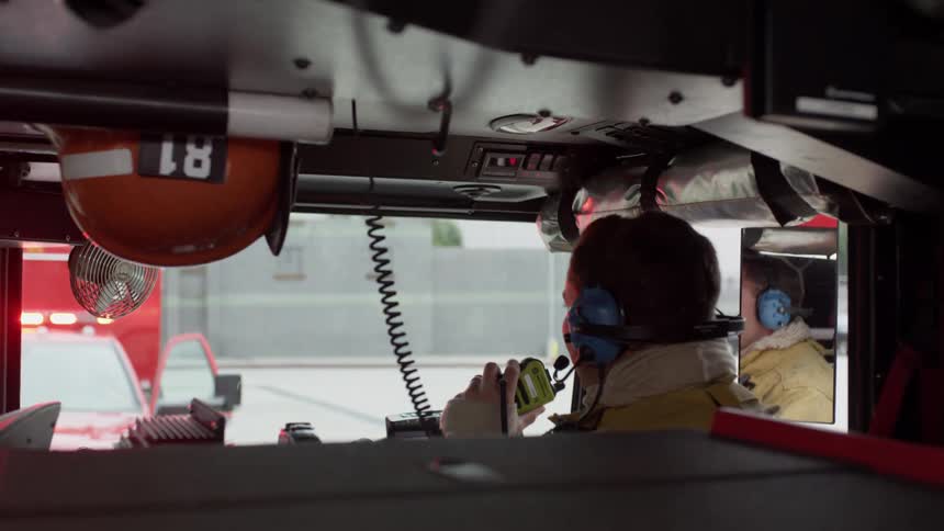 A firefighter talks on a radio in a firetruck