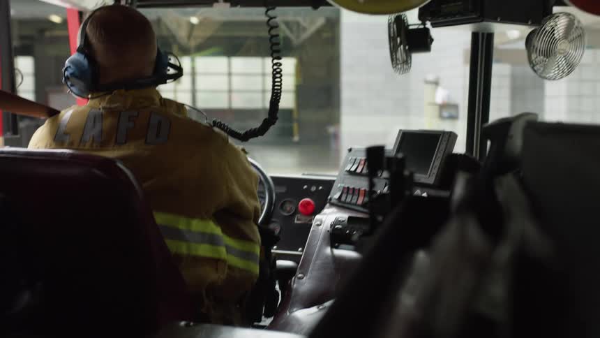 A firefighter drives a fire truck to the station