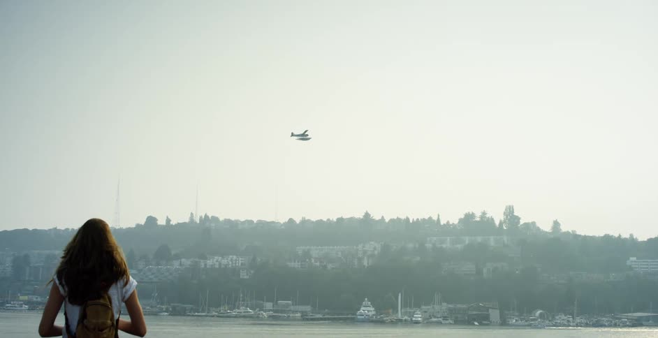 Woman walks towards a hill as a plane flies overhead