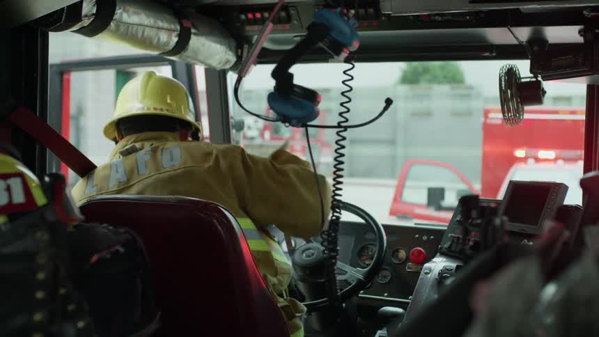 A firefighter grabs his helmet and gets out of the firetruck