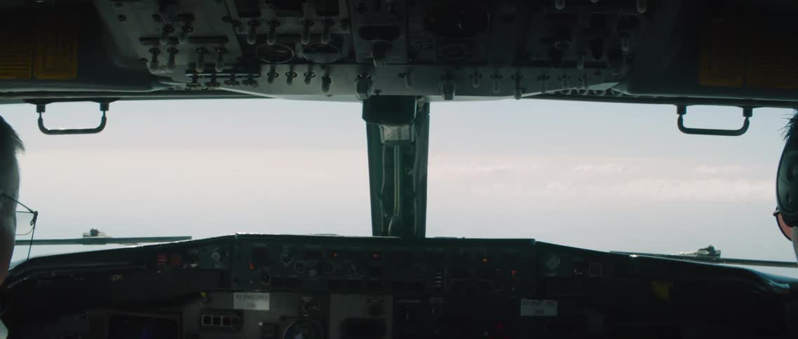 Two white males sit in a cockpit piloting an aircraft