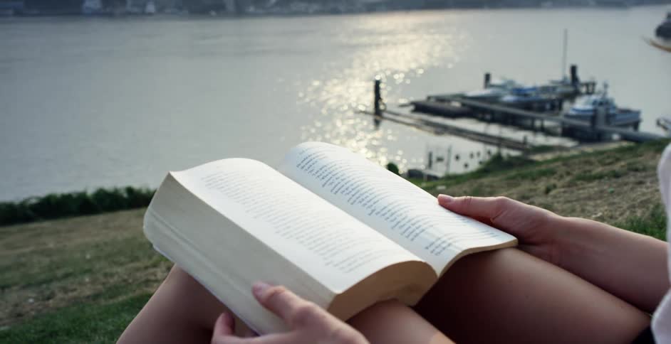 Female reading on a grassy hillside overlooking the lake