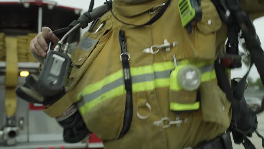 Firefighter equips with gear near a fire truck