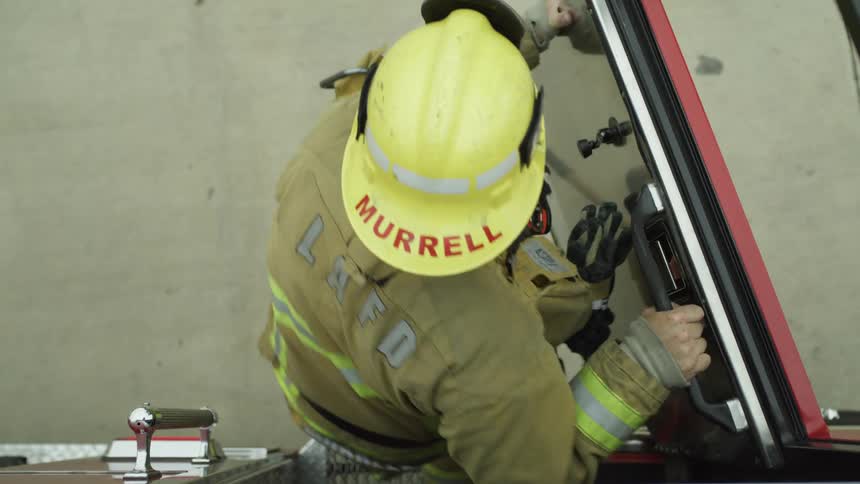 Firefighter exits a fire truck then closes the door then walks away