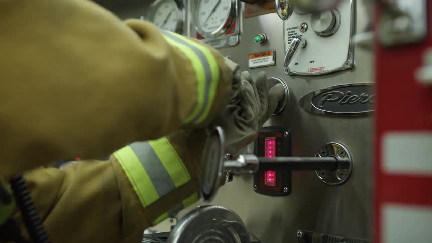 A firefighter turns the knob on the fire truck