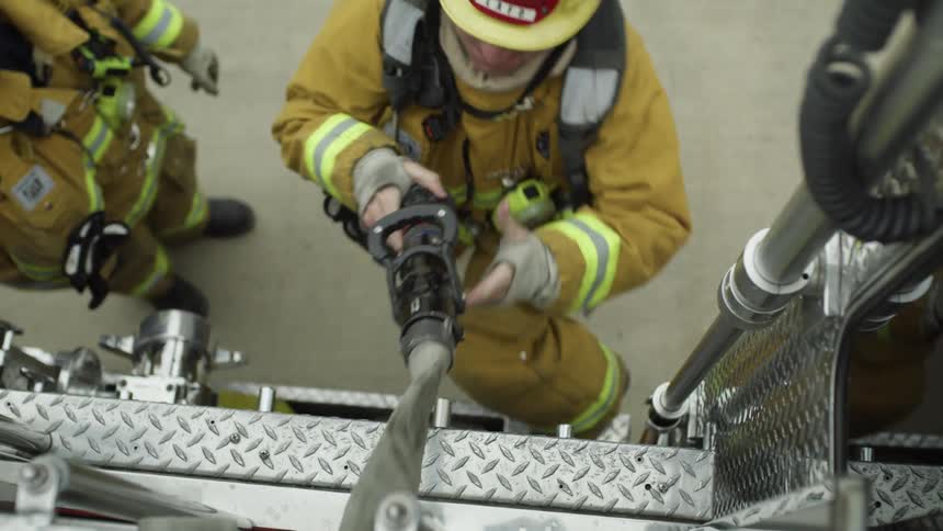 A firefighter climbs on the truck to pull the hose out