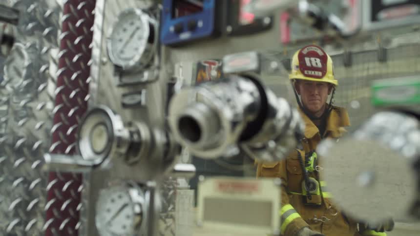 A firefighter stands and looks at equipment