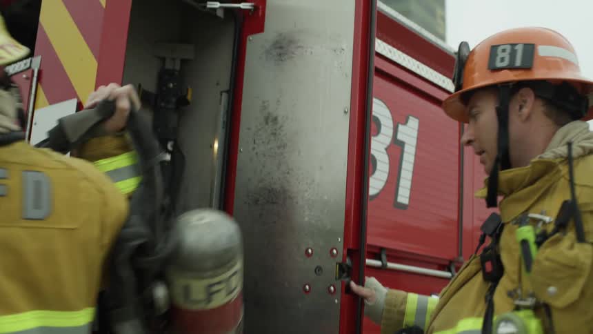 Firefighters run to fire truck to take out equipment