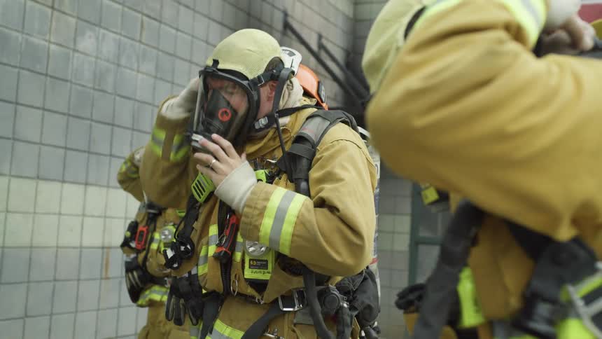 Three firefighters putting masks and helmets on