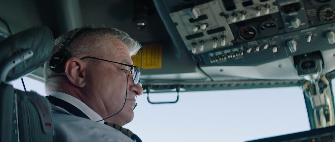 A man is flying an airplane wearing glasses