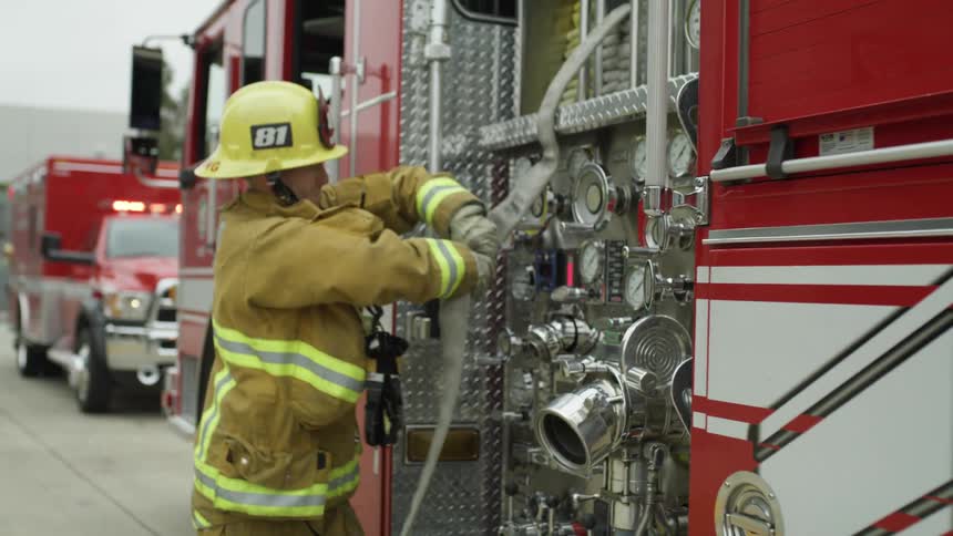 A firefighter pulls a hose off the truck