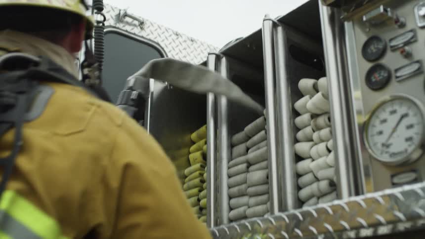 Firefighter grabs firehouse from fire engine and pulls it along with them