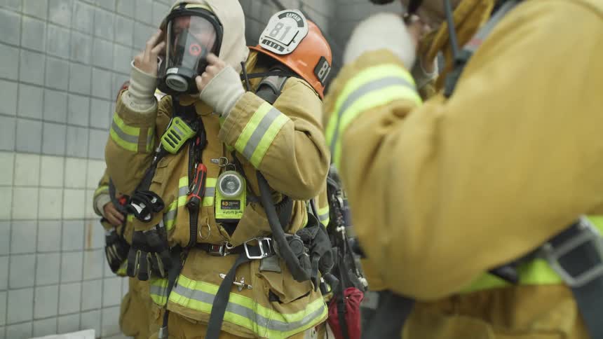 Three firefighters stand inside and put their gear on