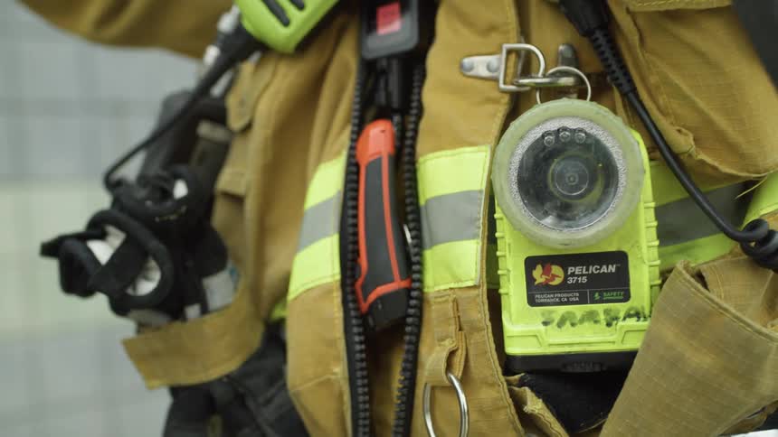 A firefighter adjusts equipment attached to his uniform