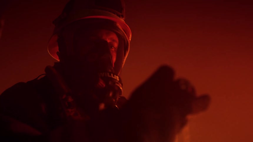 Firefighter reads equipment on a smoke filled room near a fire