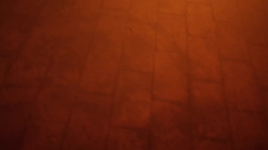 A flame burns close to a dirty brick floor